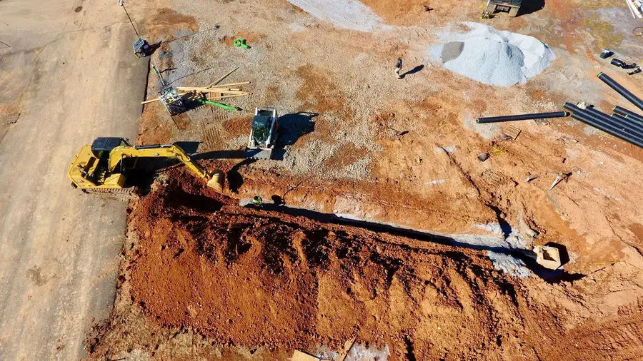 Excavator installing HDPE storm pipe in an open trench